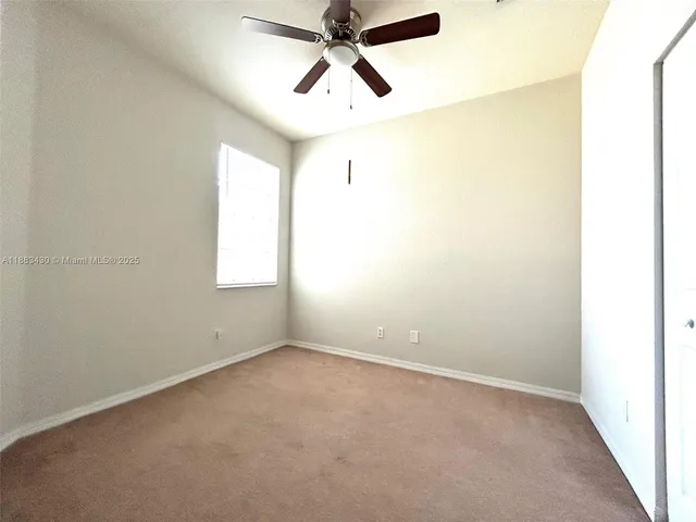 an empty room with chandelier fan and windows