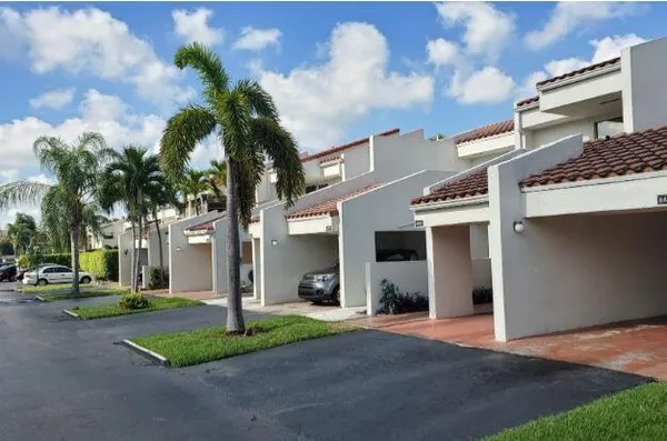 a front view of a house with garden and parking