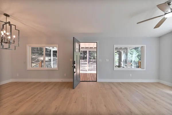 a view of an empty room with a window and wooden floor