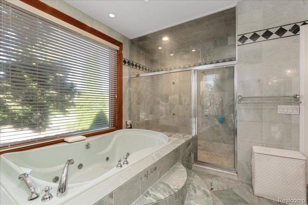3543 Cedar Brook Drive Rochester, MI 48309 - Photo 64 of 99 Jetted soaking tub, glass-enclosed shower, extensive stone tilework, recessed lighting, and a large window with horizontal blinds