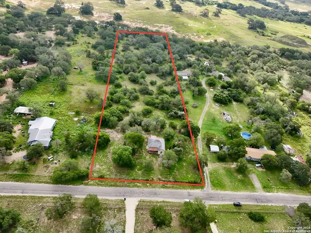 an aerial view of residential houses with outdoor space and trees