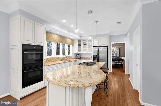 a kitchen with stainless steel appliances granite countertop a stove a sink and a refrigerator with wooden floor