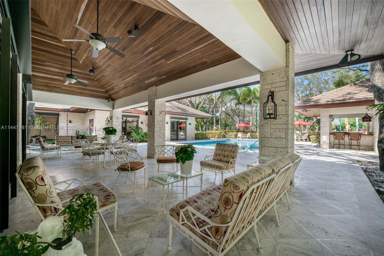 4875 Southwest 80th Street Miami, FL 33143 - Photo 34 of 52 a view of a patio with chairs and tables under an umbrella next to a yard