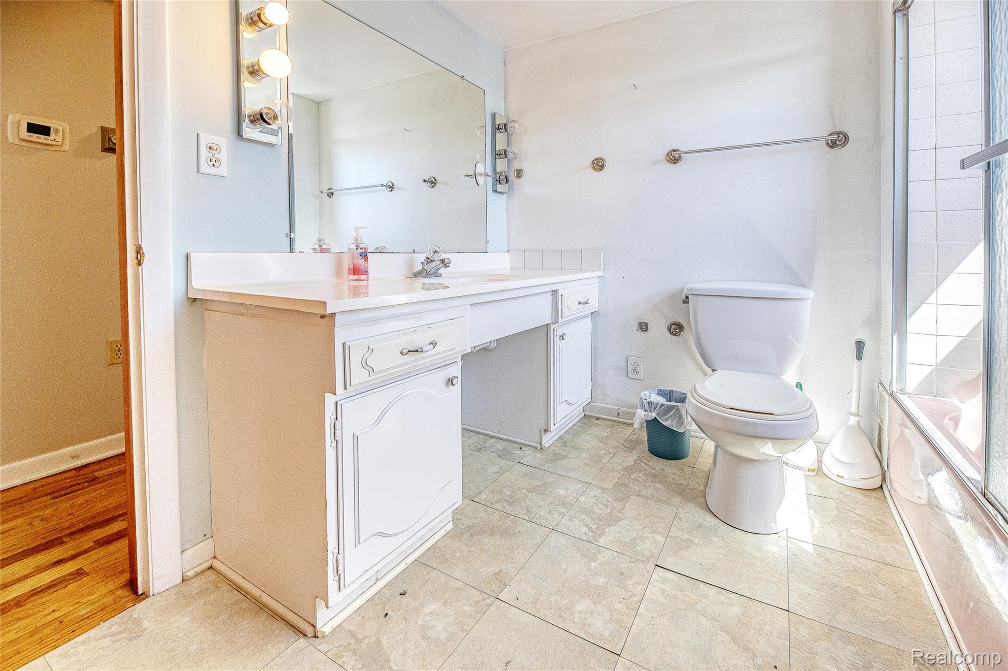 2855 Farmers Creek Road Metamora, MI 48455 - Photo 22 of 51 Bathroom featuring a white vanity with built-in cabinetry, a large wall-mounted mirror, overhead vanity lighting, and tiled flooring
