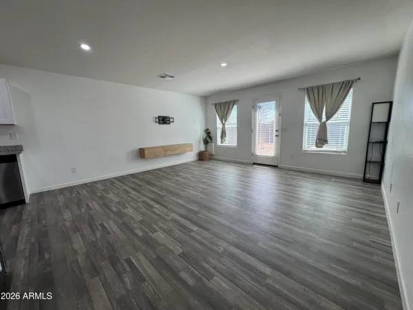 an empty room with wooden floor and windows