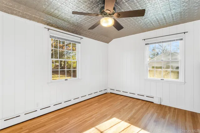 an empty room with wooden floor fan and windows