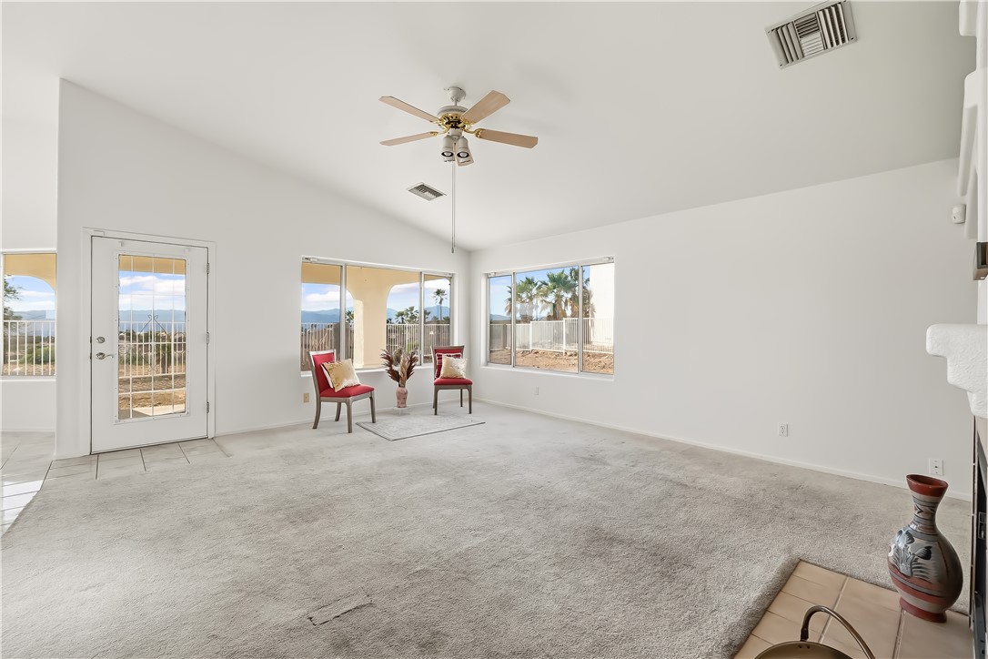 2853 Winchester Road Bullhead City, AZ 86442 - Photo 15 of 40 Spacious room featuring a vaulted ceiling with a ceiling fan, light-colored carpet flooring, and multiple large windows