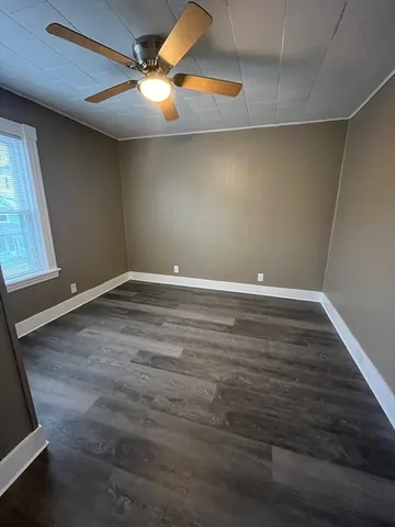 an empty room with wooden floor and fan