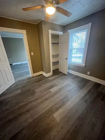 an empty room with wooden floor cabinet and windows