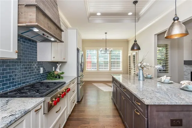a kitchen with stainless steel appliances granite countertop a sink a stove and a wooden floors