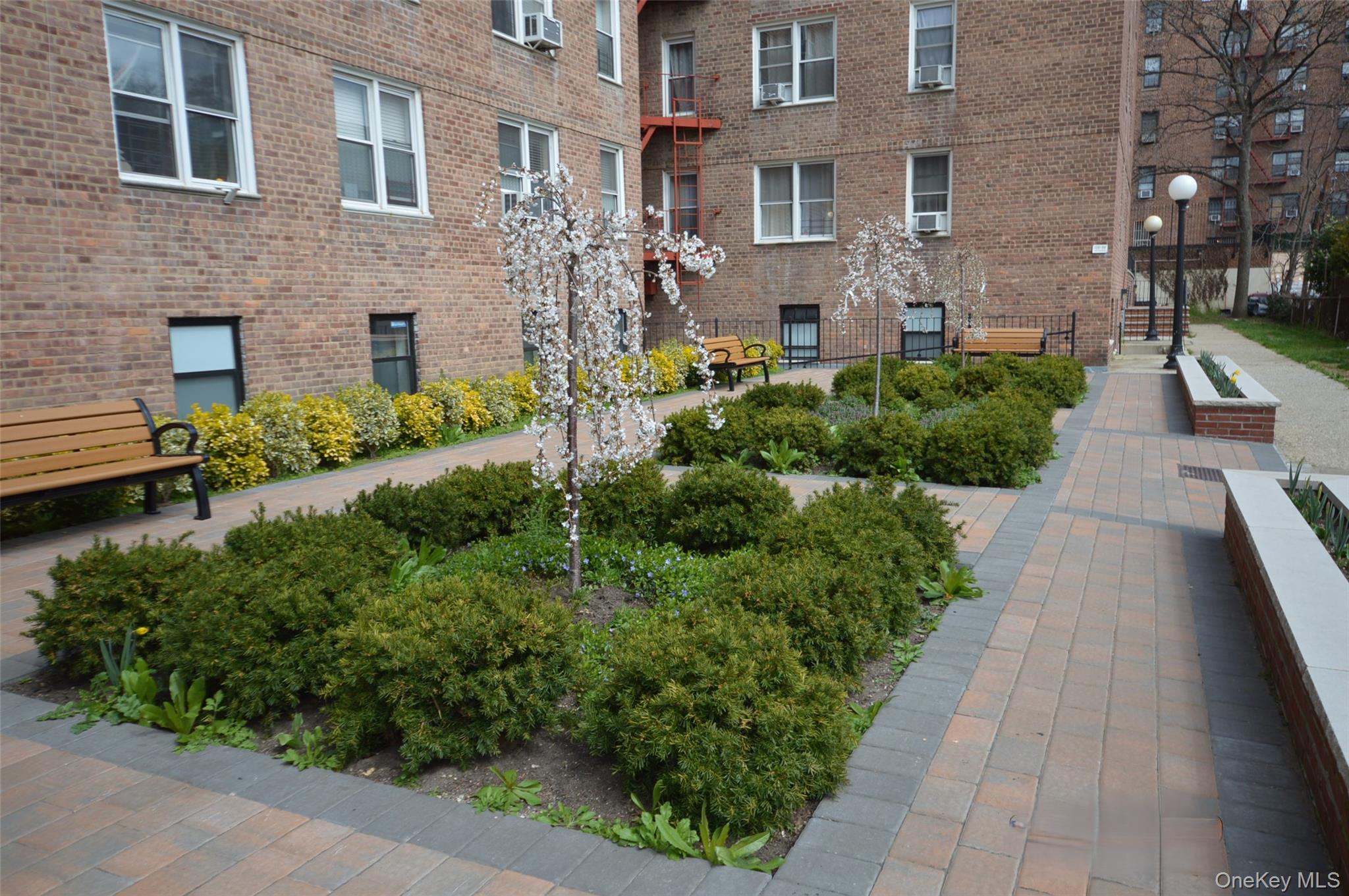 65-45 Yellowstone Boulevard, Unit 2B Queens, NY 11375 - Photo 14 of 14 a view of a brick house with a yard and plants