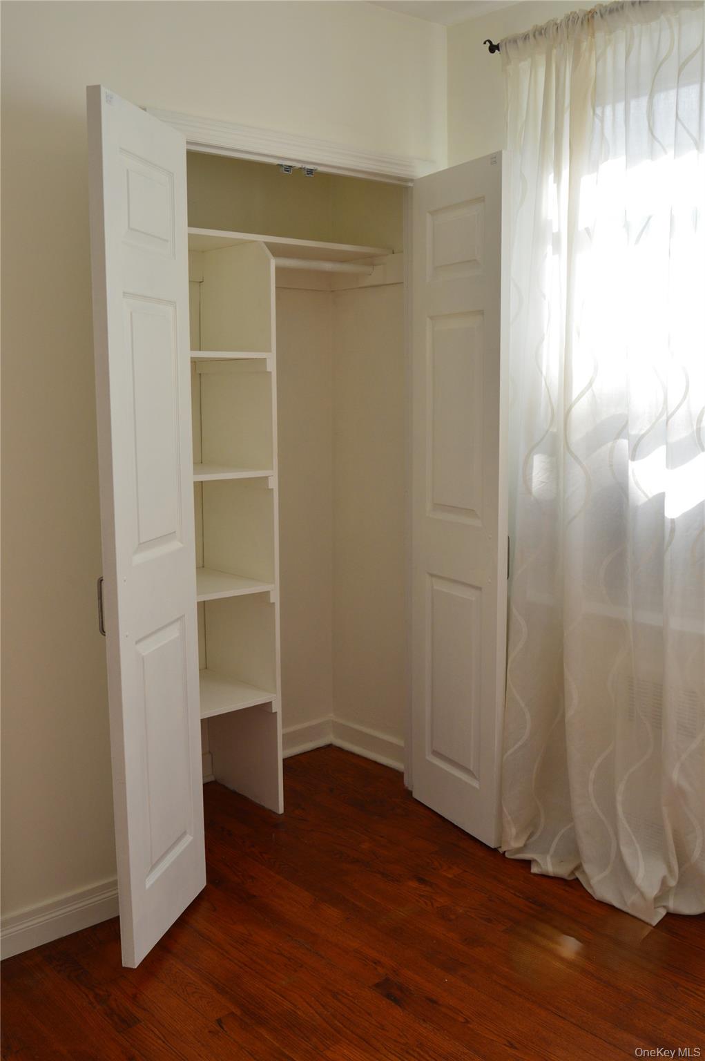 65-45 Yellowstone Boulevard, Unit 2B Queens, NY 11375 - Photo 7 of 14 a view of an empty room with wooden floor and a window