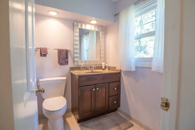 a bathroom with a granite countertop toilet sink and mirror