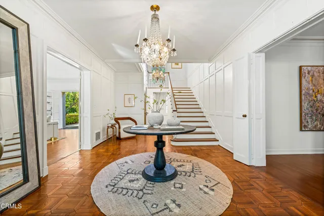 a dining room with wooden floor a chandelier a wooden table and chairs