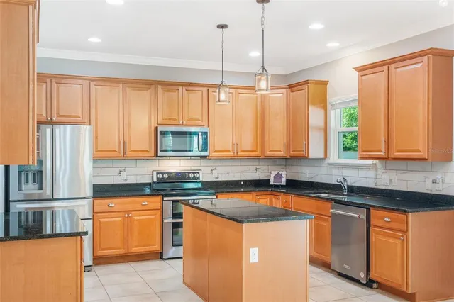 a kitchen with stainless steel appliances granite countertop a sink a stove and a refrigerator