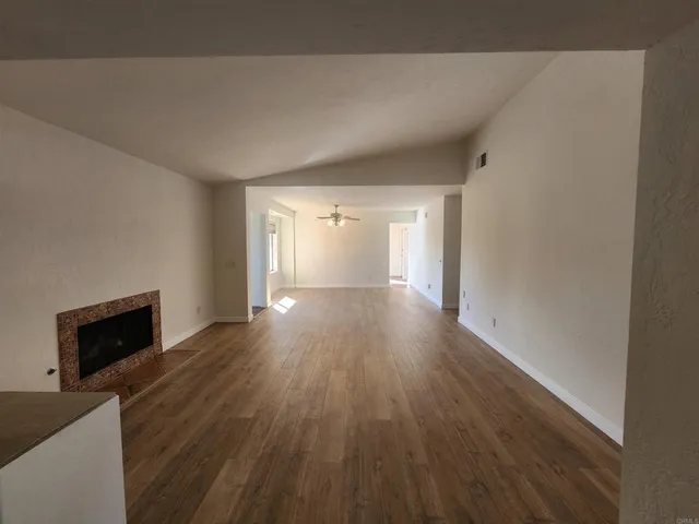 a view of empty room with wooden floor and fireplace