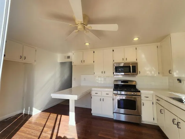 a kitchen with stainless steel appliances kitchen island granite countertop a stove a sink and white cabinets
