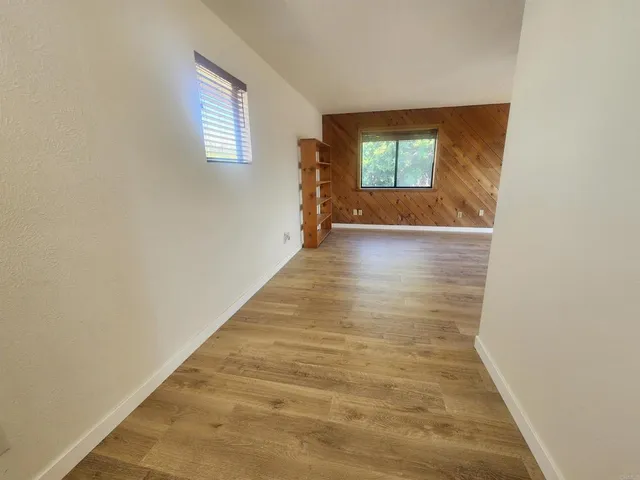a view of hallway with window and hardwood floor