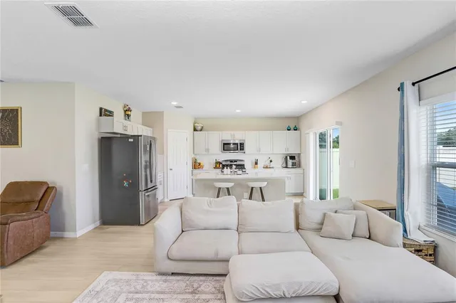 a living room with furniture and a refrigerator