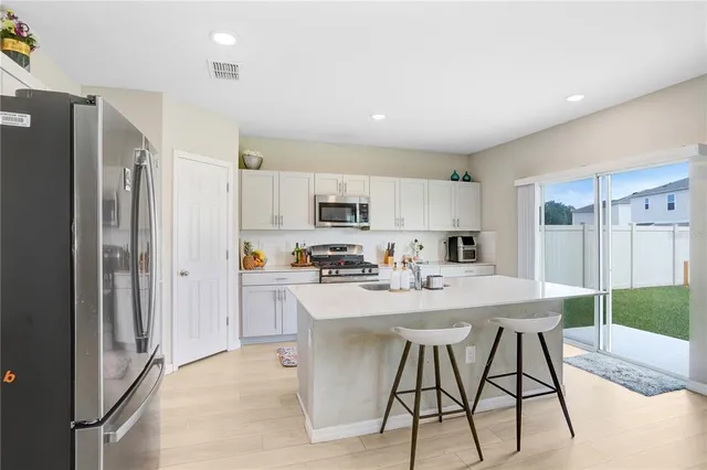 a kitchen with stainless steel appliances kitchen island granite countertop a refrigerator and a stove top oven