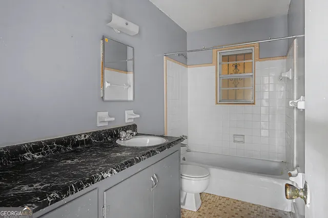 a bathroom with a granite countertop sink a toilet and shower