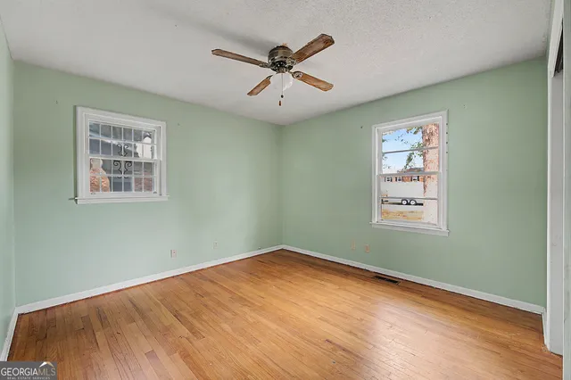 a view of a big room with wooden floor and windows