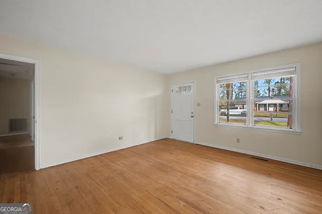an empty room with wooden floor and windows