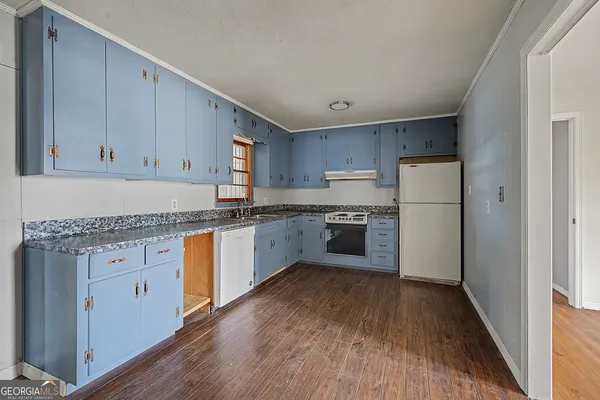 a kitchen with granite countertop white cabinets and white appliances