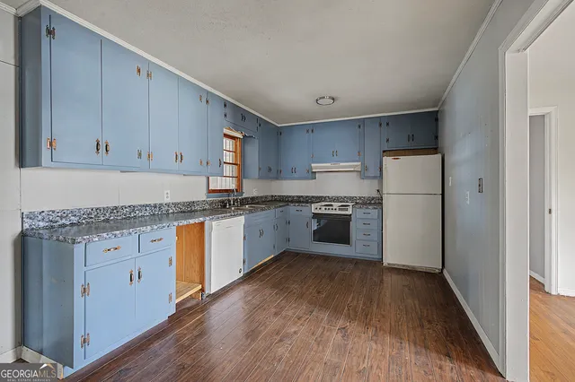 a kitchen with granite countertop white cabinets and white appliances