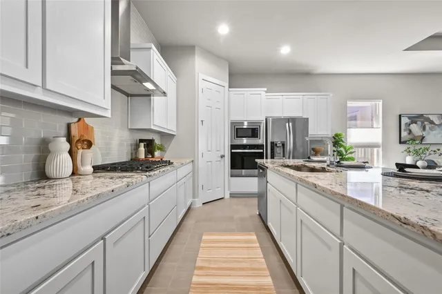 a large kitchen with stainless steel appliances granite countertop a lot of counter space and wooden floors
