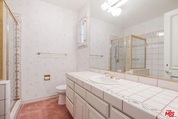 a bathroom with a granite countertop sink a toilet and shower