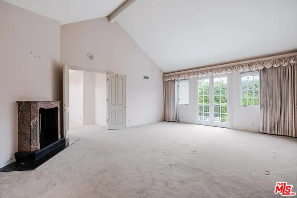 a view of an empty room with a fireplace and a window