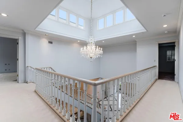 a view of a hallway with stairs and chandelier