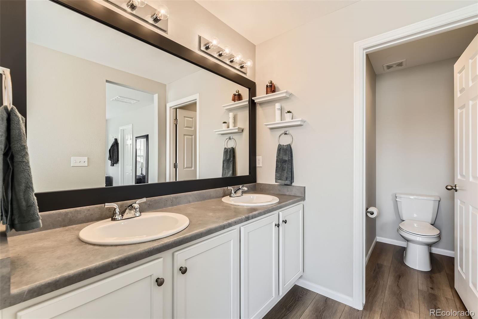 25621 East Cedar Place Aurora, CO 80018 - Photo 15 of 30 a bathroom with a granite countertop sink a toilet and a mirror