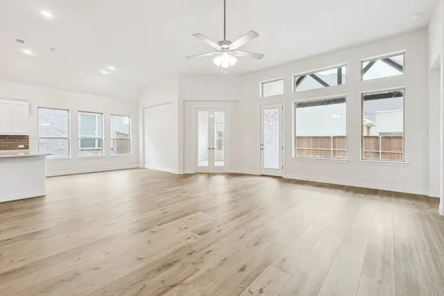 a view of an empty room with window and wooden floor