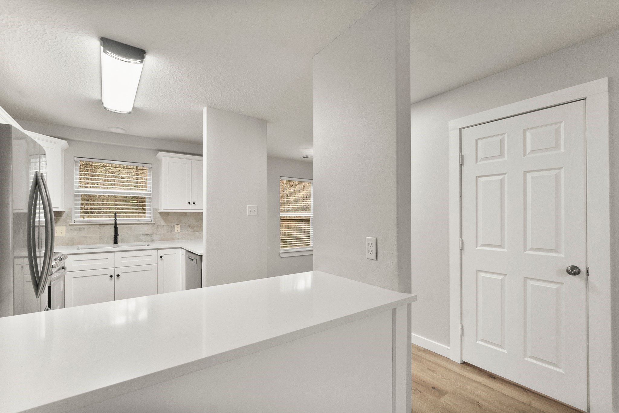 1799 League Line Road, Unit 4 Conroe, TX 77304 - Photo 3 of 34 a large white kitchen with granite countertop a sink dishwasher a stove and a refrigerator with wooden floor