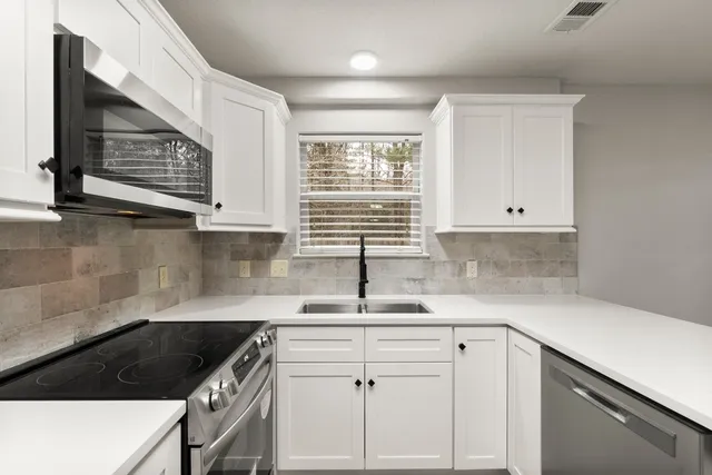 a kitchen with granite countertop a sink a stove and cabinets