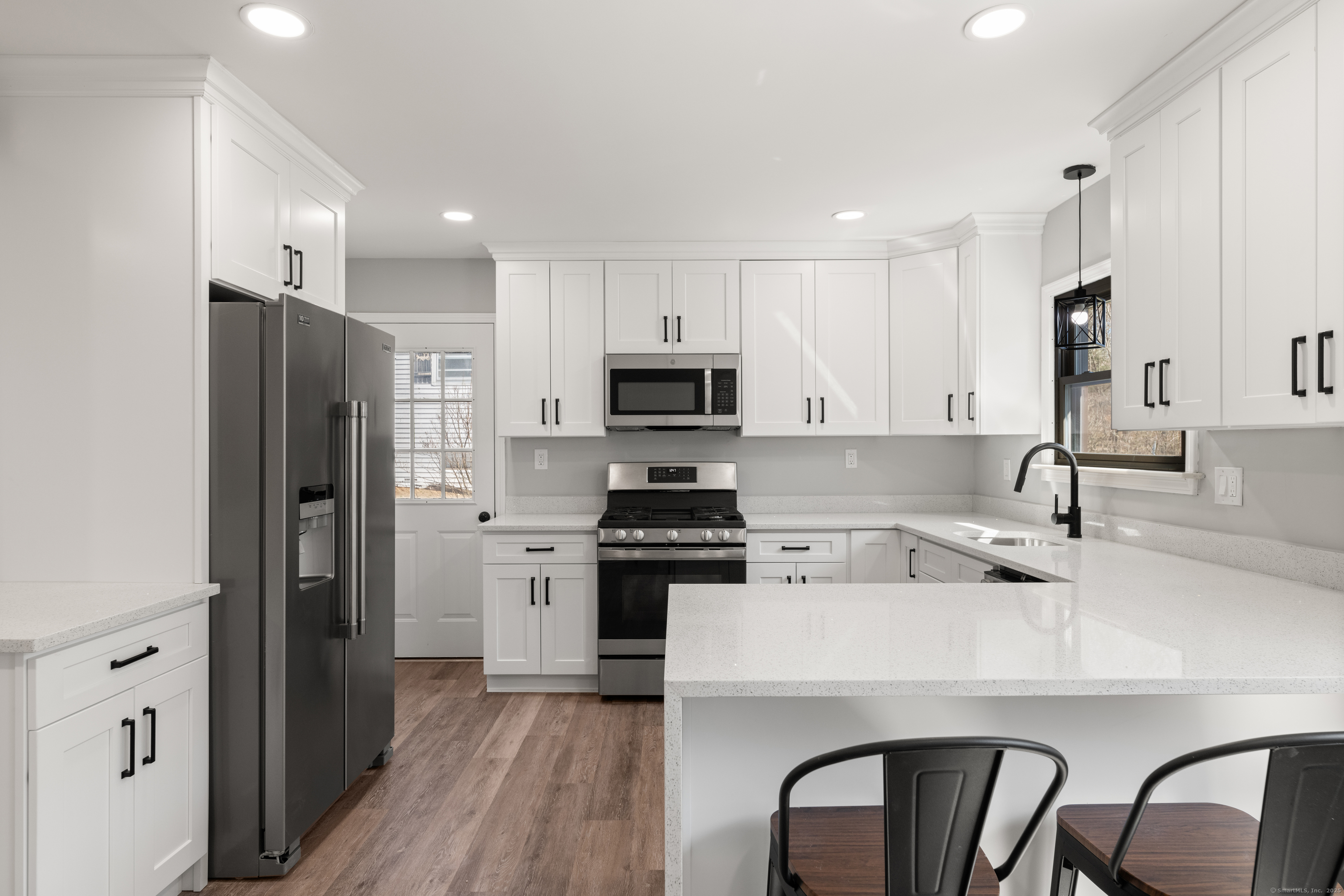 a kitchen with a refrigerator a stove a sink and chairs with wooden floor