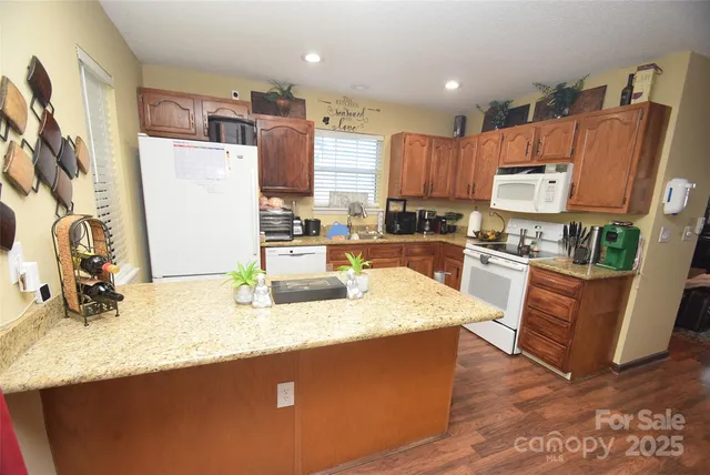 a kitchen with stainless steel appliances granite countertop a sink dishwasher a refrigerator and a stove with wooden floor