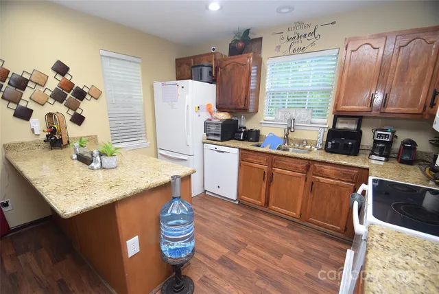 a kitchen with granite countertop a sink appliances cabinets and wooden floor