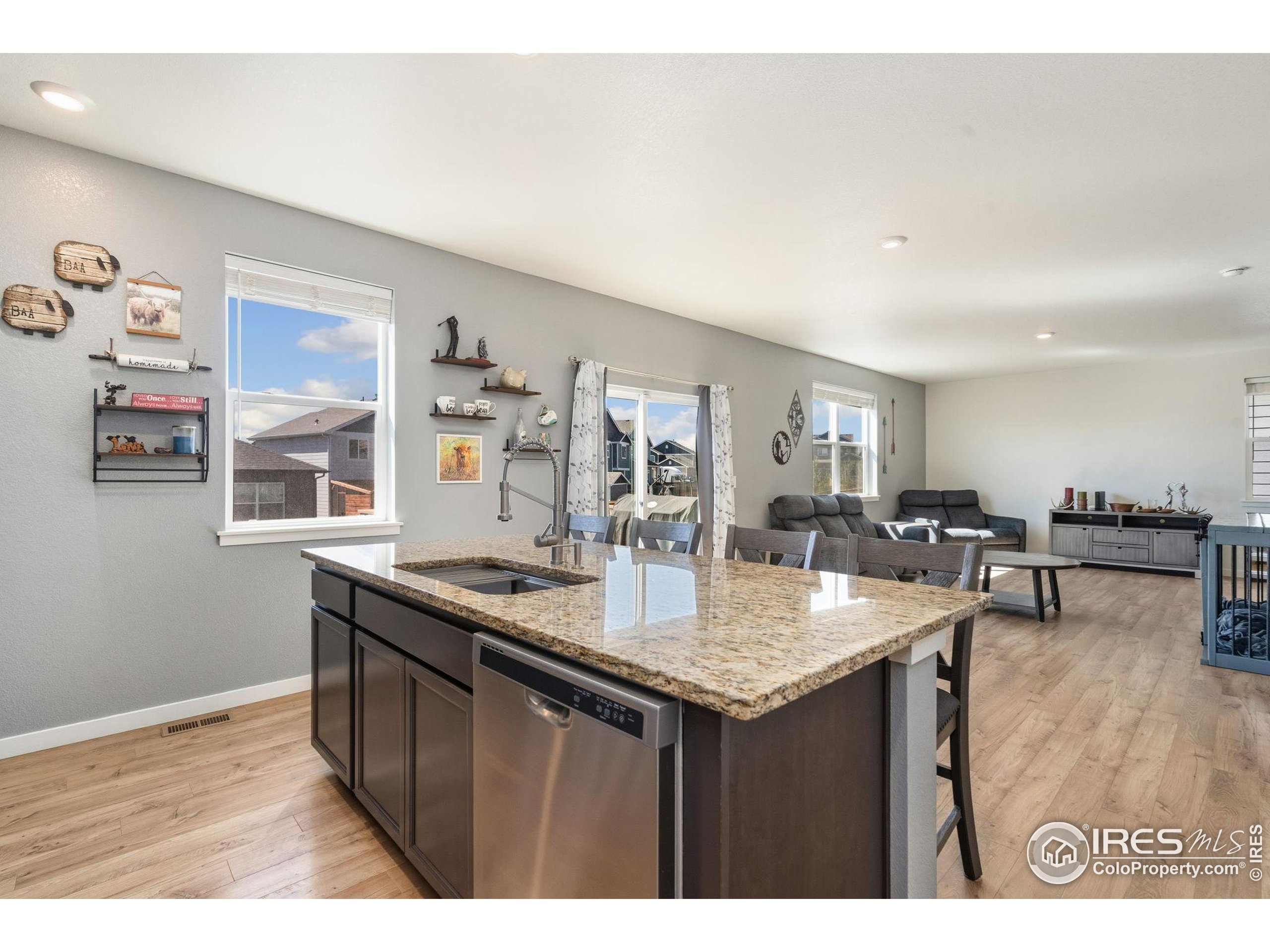 1233 Lily Mountain Road Severance, CO 80550 - Photo 11 of 44 a dining hall with granite countertop a sink dishwasher a dining table and chairs with wooden floor
