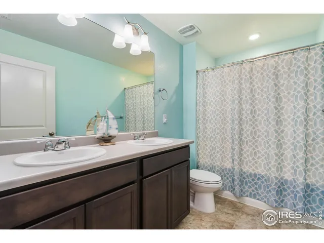 a bathroom with a double vanity sink toilet and a mirror