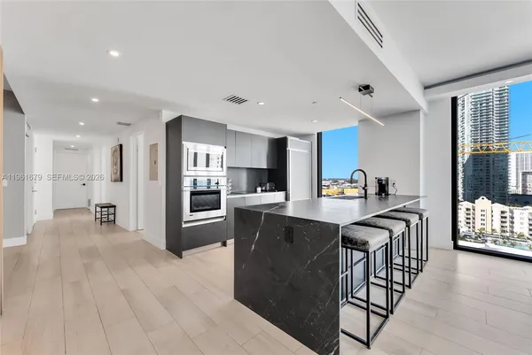 a kitchen with stainless steel appliances granite countertop a refrigerator a stove top oven a sink dishwasher and white cabinets with wooden floor