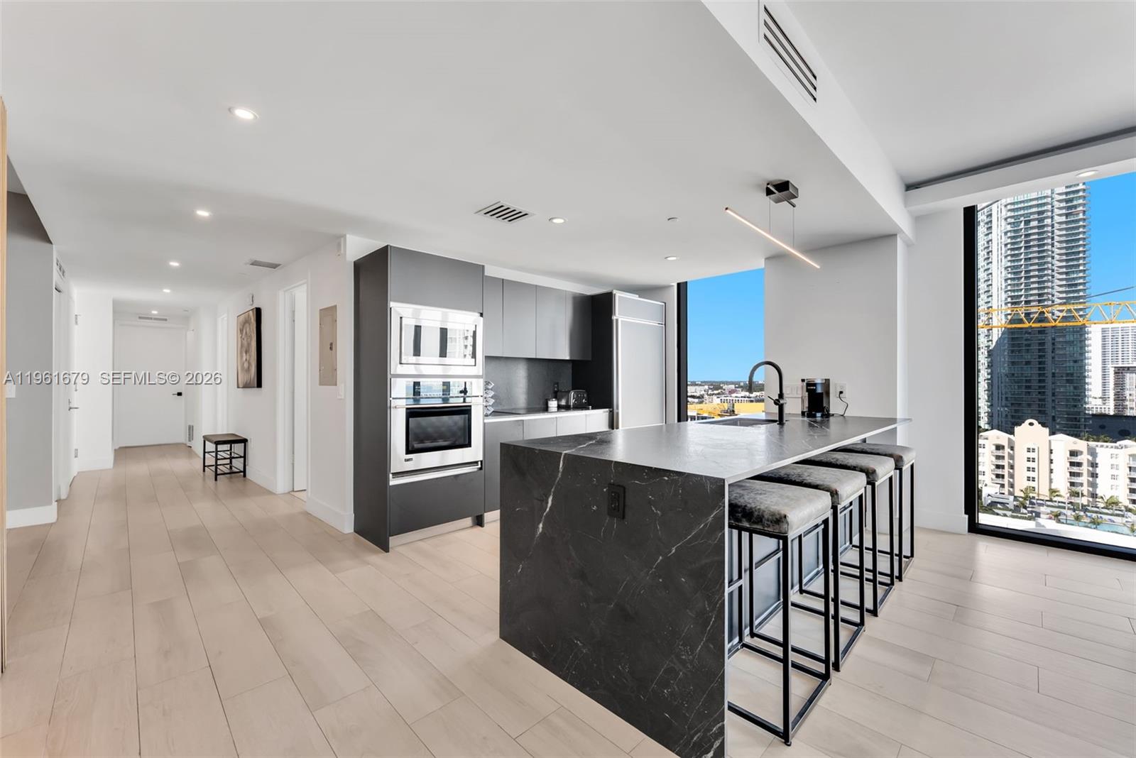 460 Northeast 28th Street, Unit 1601 Miami, FL 33137 - Photo 8 of 41 a kitchen with stainless steel appliances granite countertop a refrigerator a stove top oven a sink dishwasher and white cabinets with wooden floor