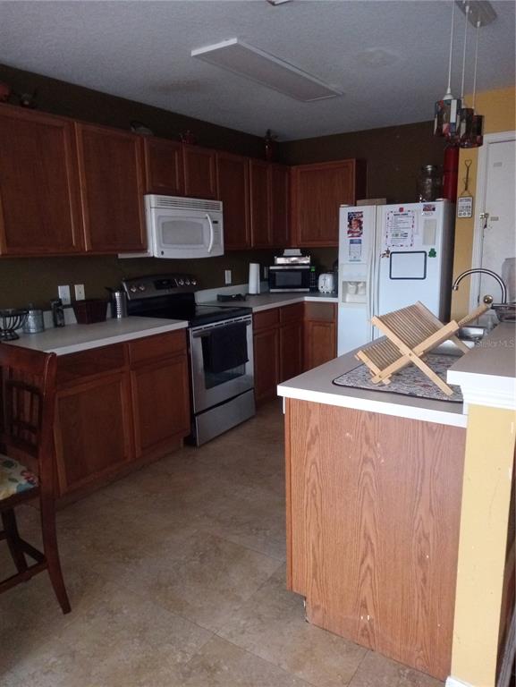 10933 Subtle Trail Drive Riverview, FL 33579 - Photo 6 of 22 a kitchen with stainless steel appliances granite countertop a stove top oven a sink dishwasher and a refrigerator with wooden cabinets