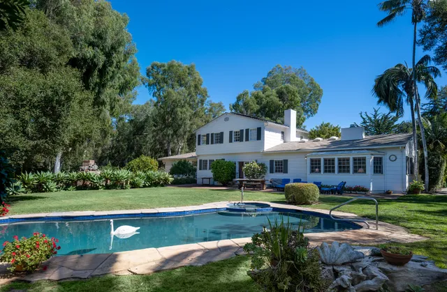 a view of house with garden and tall trees