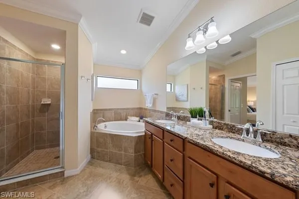 a bathroom with a granite countertop double vanity sink mirror and shower