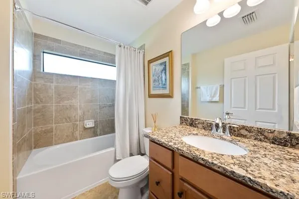 a bathroom with a granite countertop sink a toilet a mirror and bathtub