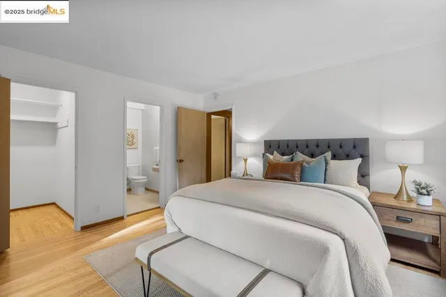 a bedroom with a bed a mirror and night stand with a window