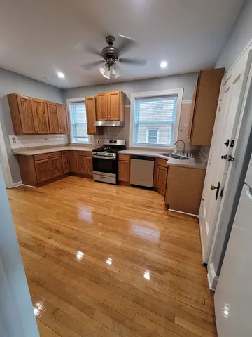 a view of kitchen with stainless steel appliances wooden floor and window